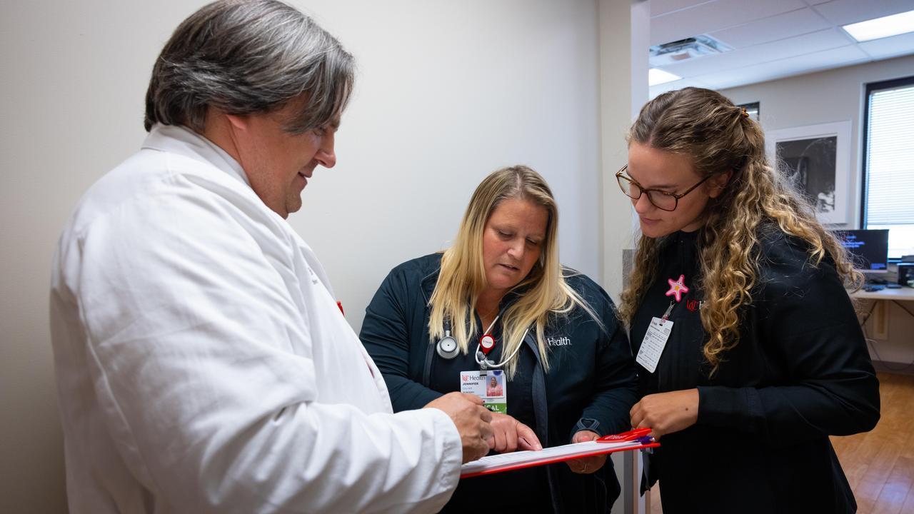 Three providers discuss information on a clipboard. 