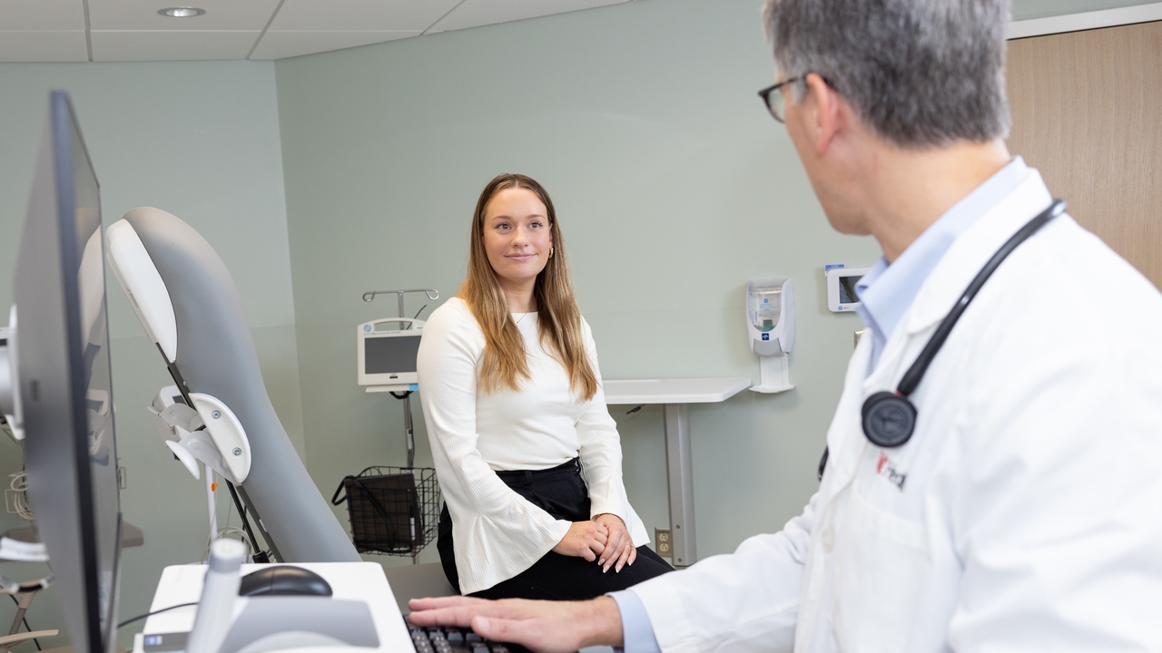 A patient talks with a physician in an exam room. 