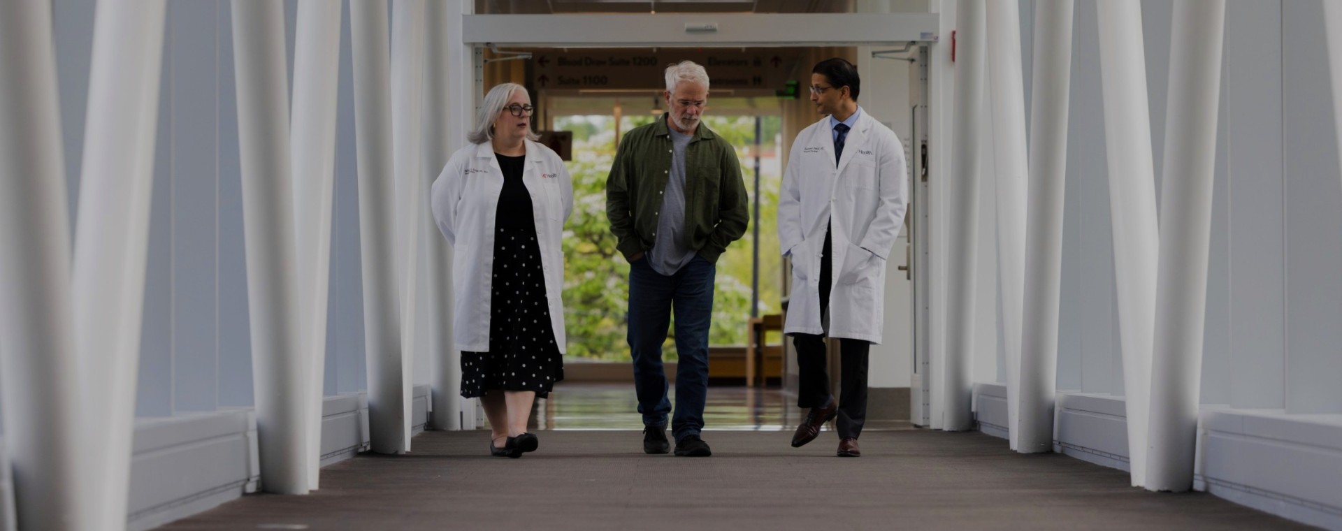 Three people walk through a hall in a medical building. 