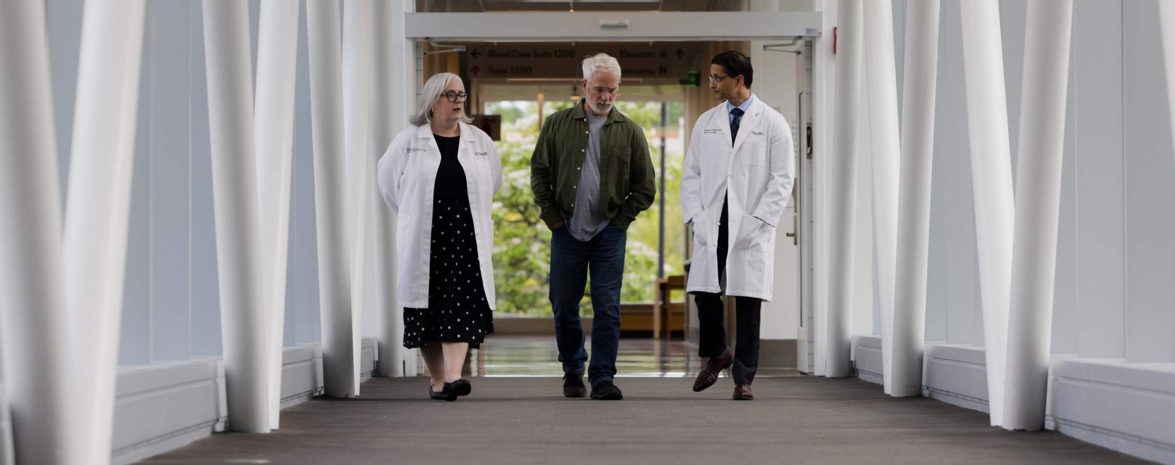 Three people walk through a hall in a medical building. 