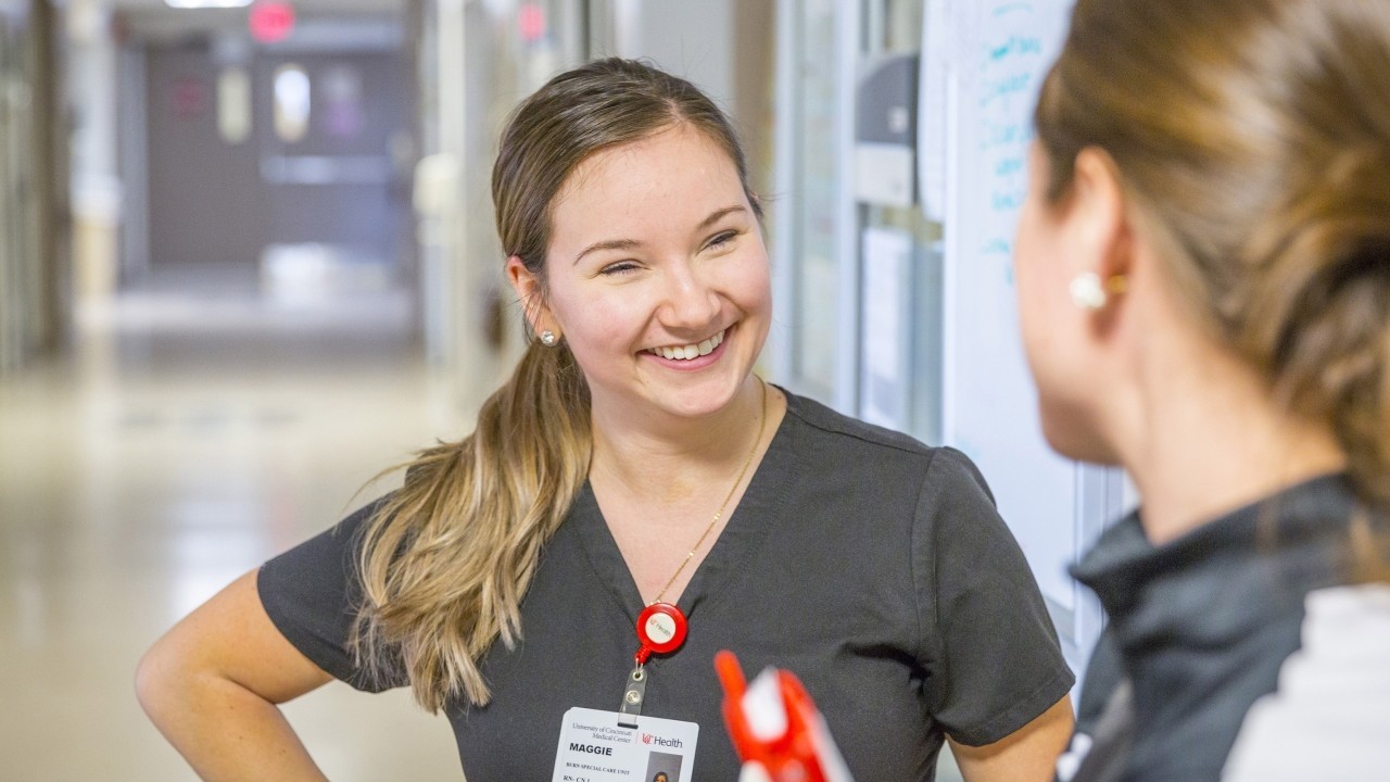 Two medical providers talk in a hallway. 