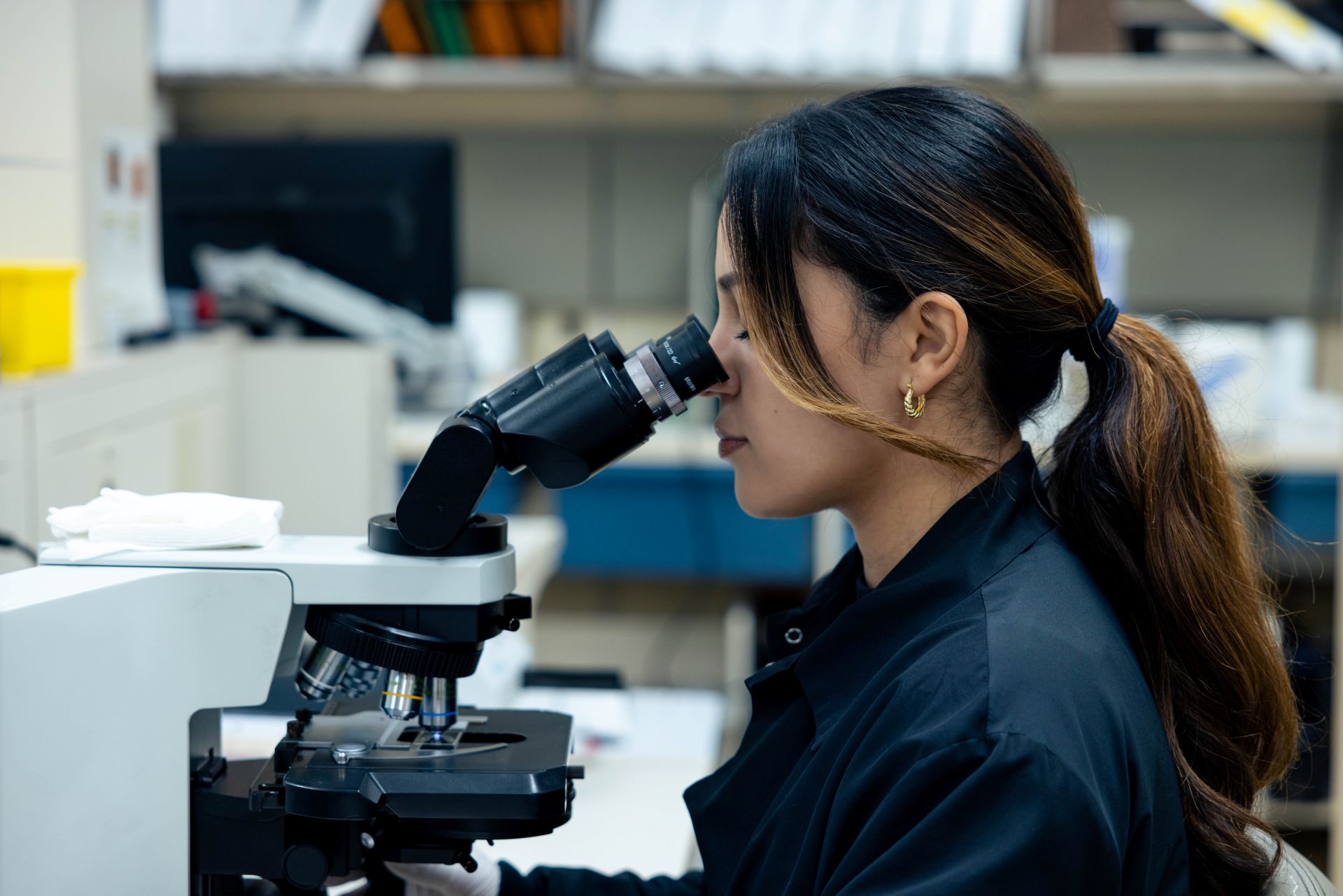 Lab specialist looks through a microscope.