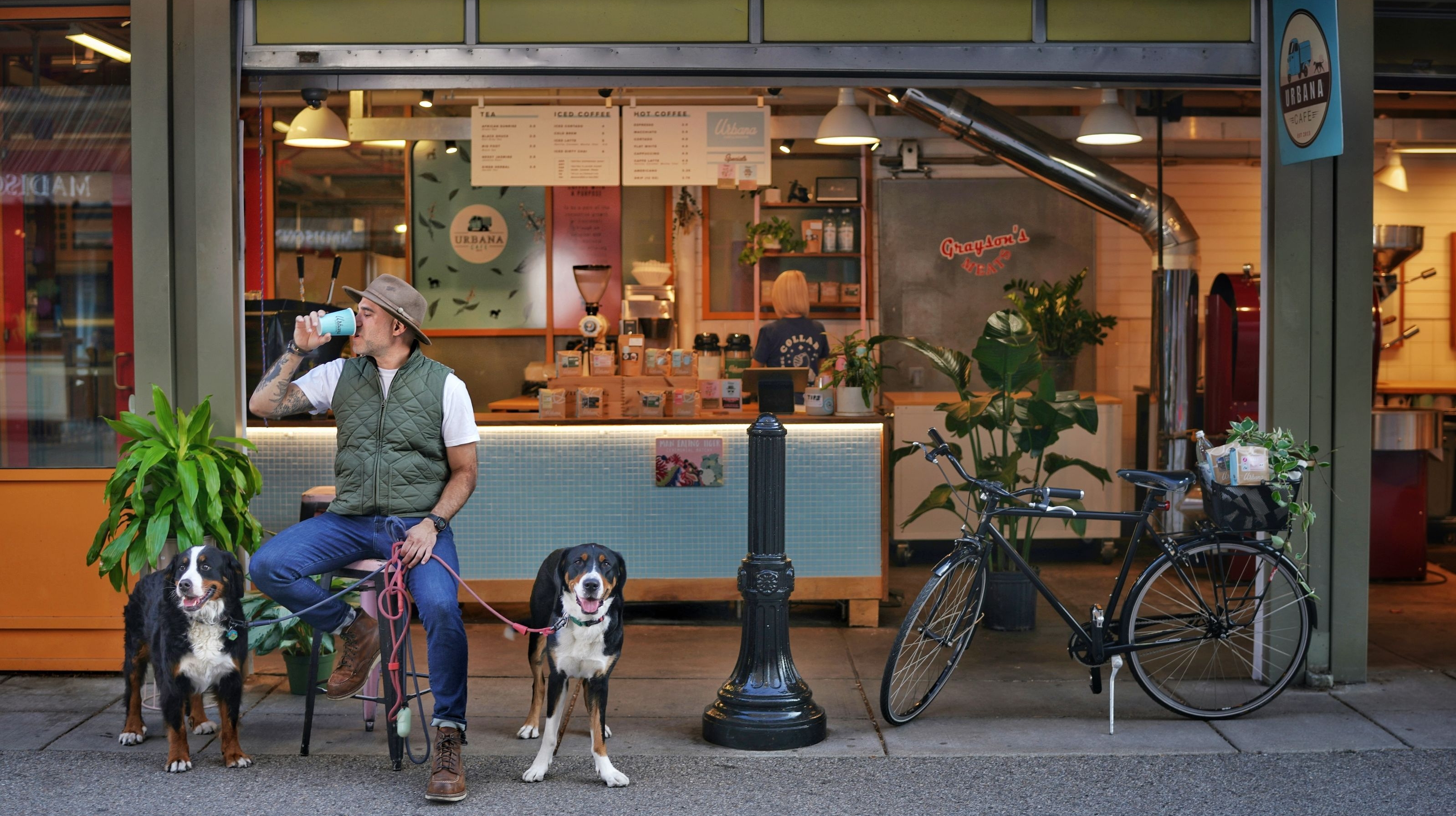 Urbana Cafe & Roaster, Findlay Market location featuring a man drinking a cup of coffee with his two dogs