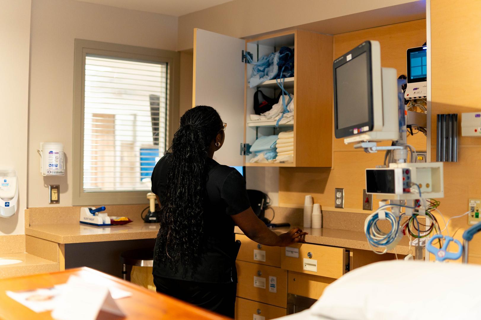 Medical Assistant stocks supplies in a patient room