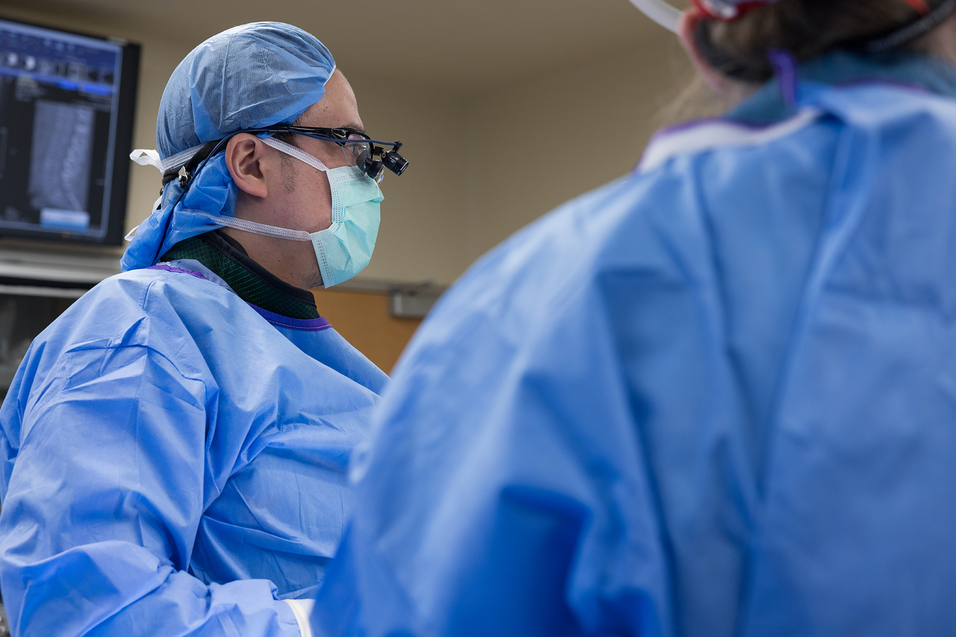 A surgeon looks at patient and x-ray images in operating room. 