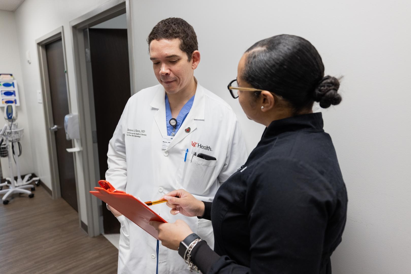 Two medical providers look at a clipboard and talk. 