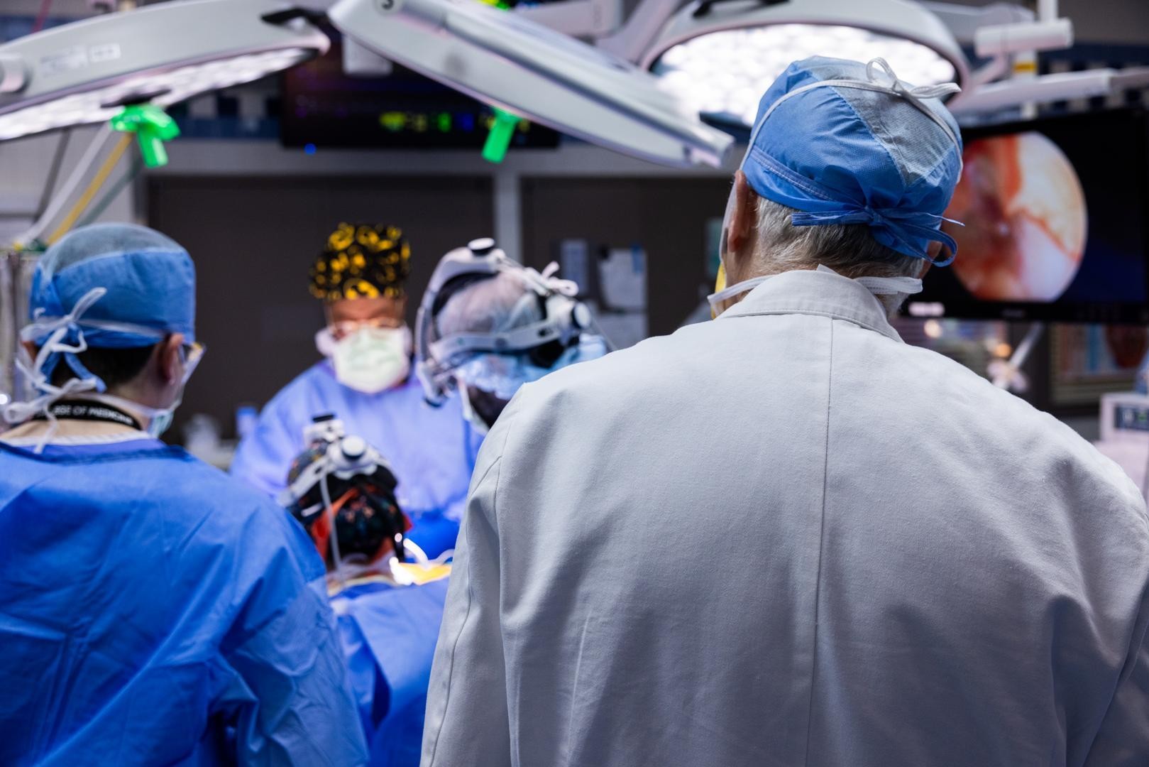 Physicians in scrubs and masks perform a medical procedure.