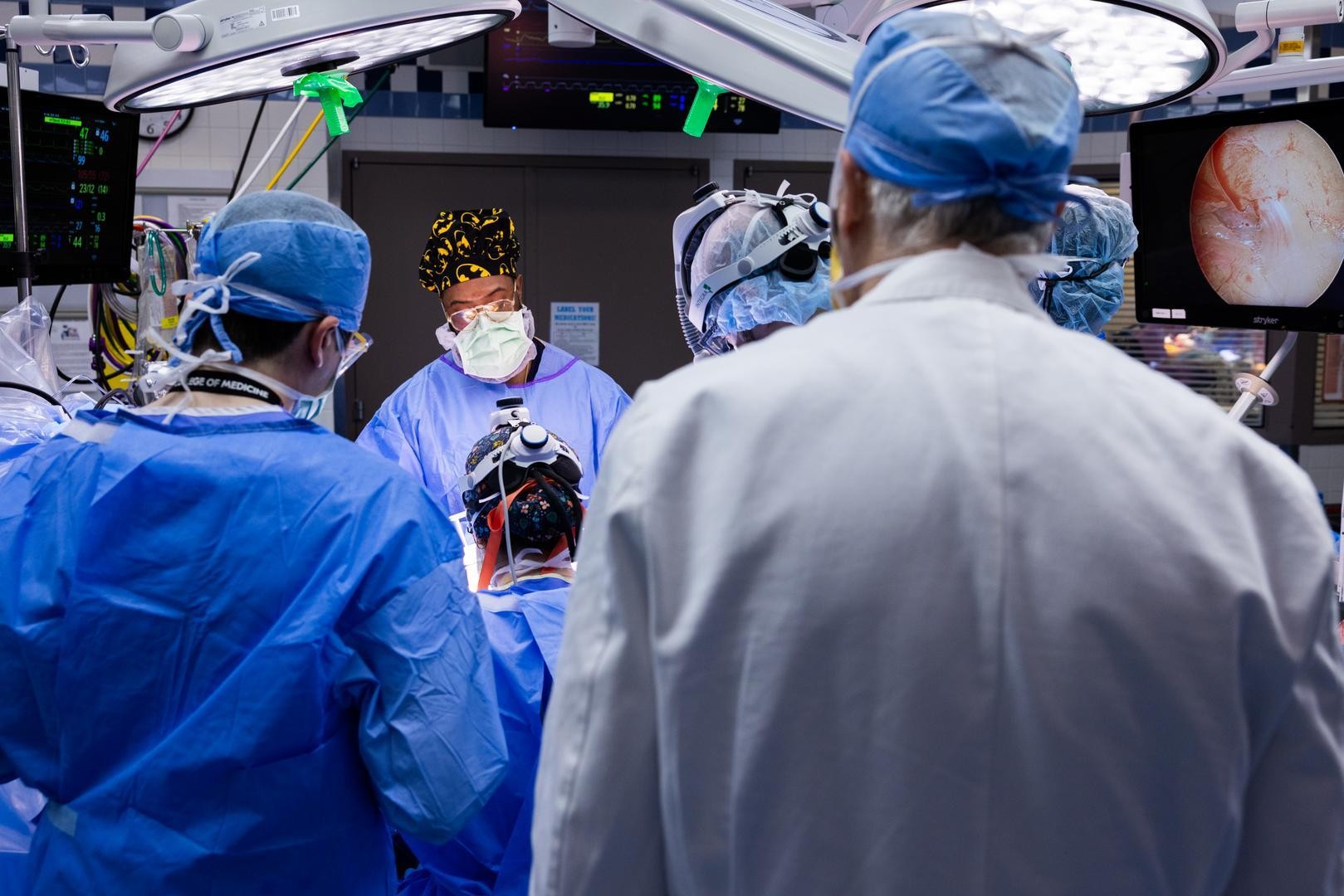 Surgeons in masks and scrubs perform a medical procedure. 