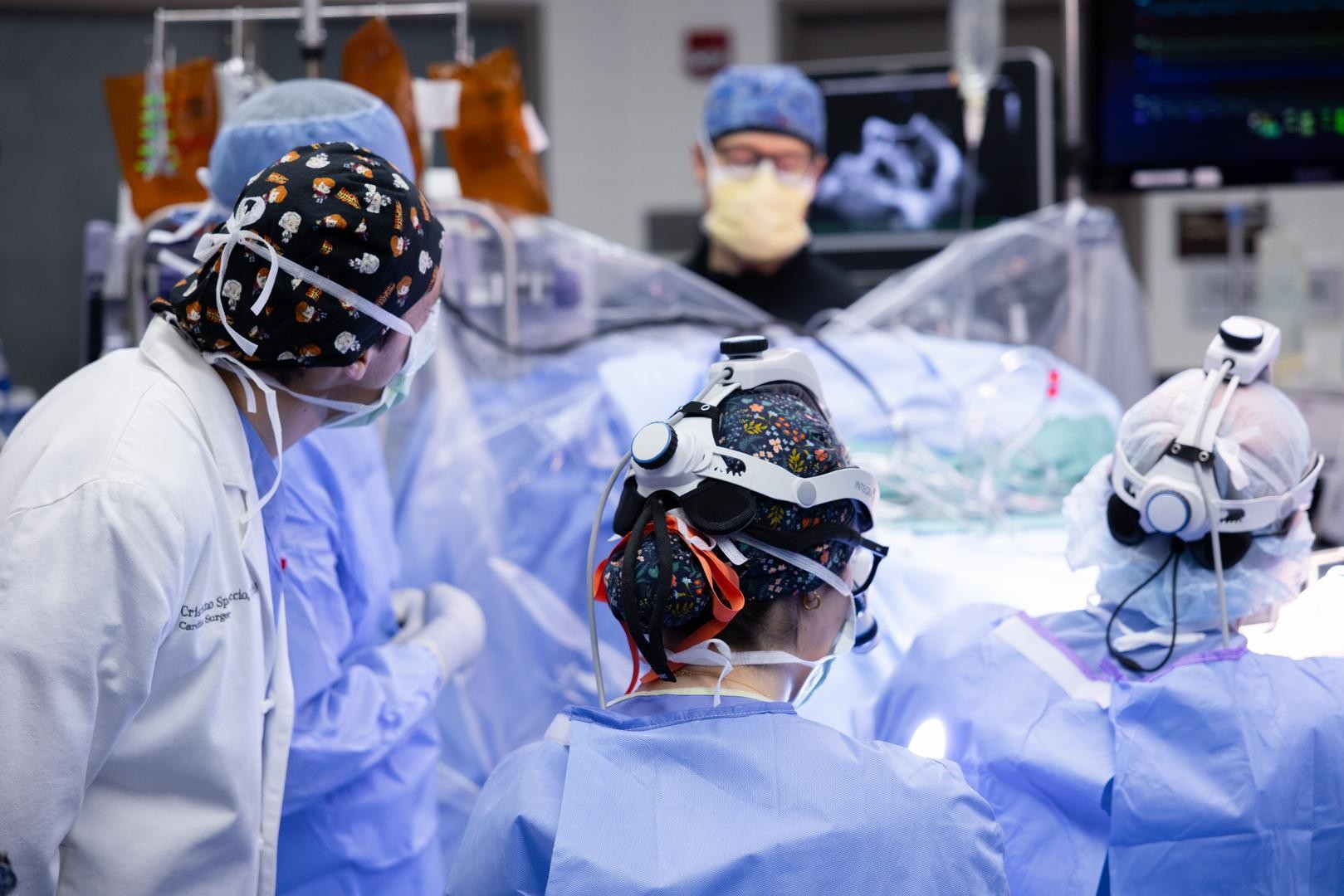 Surgeons in masks and gloves perform a medical procedure.