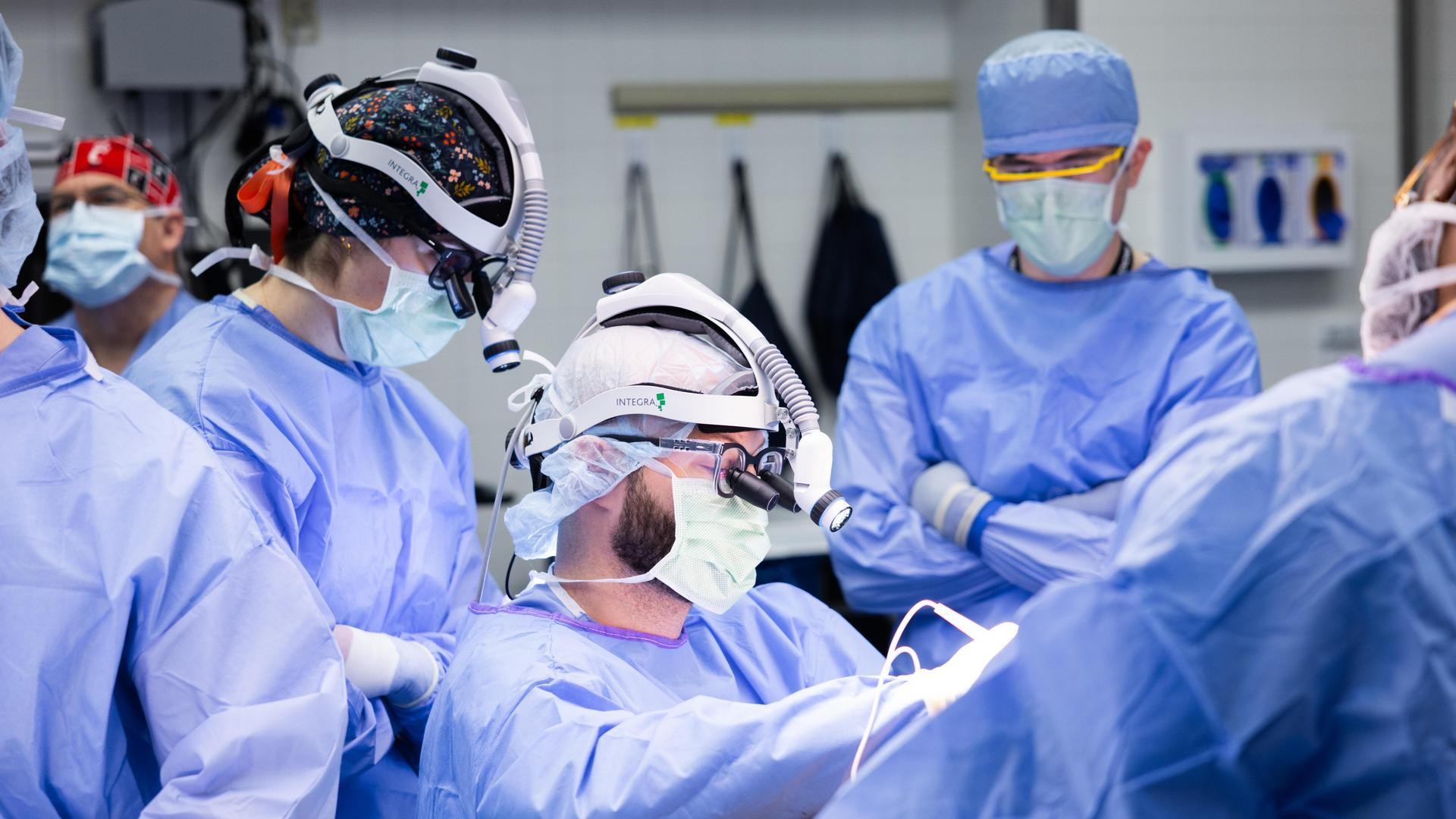 Medical providers in masks and scrubs perform surgery.