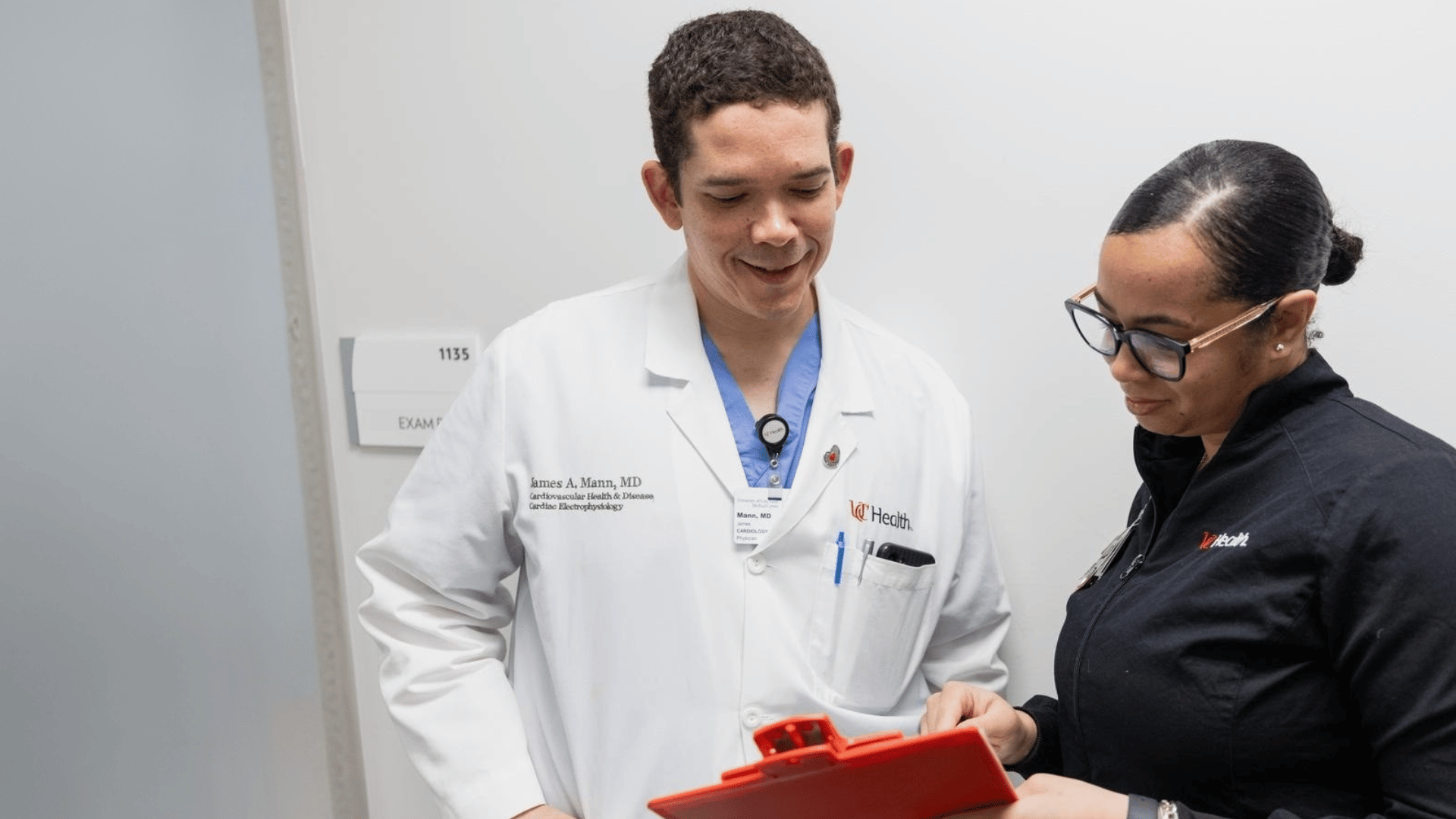 Two medical providers talk and look at a clip board