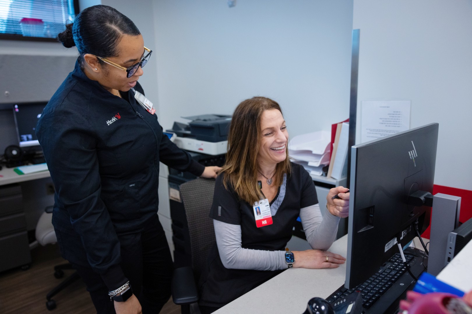 Two woman look at a monitor at a front desk at UC Health Cardiology.