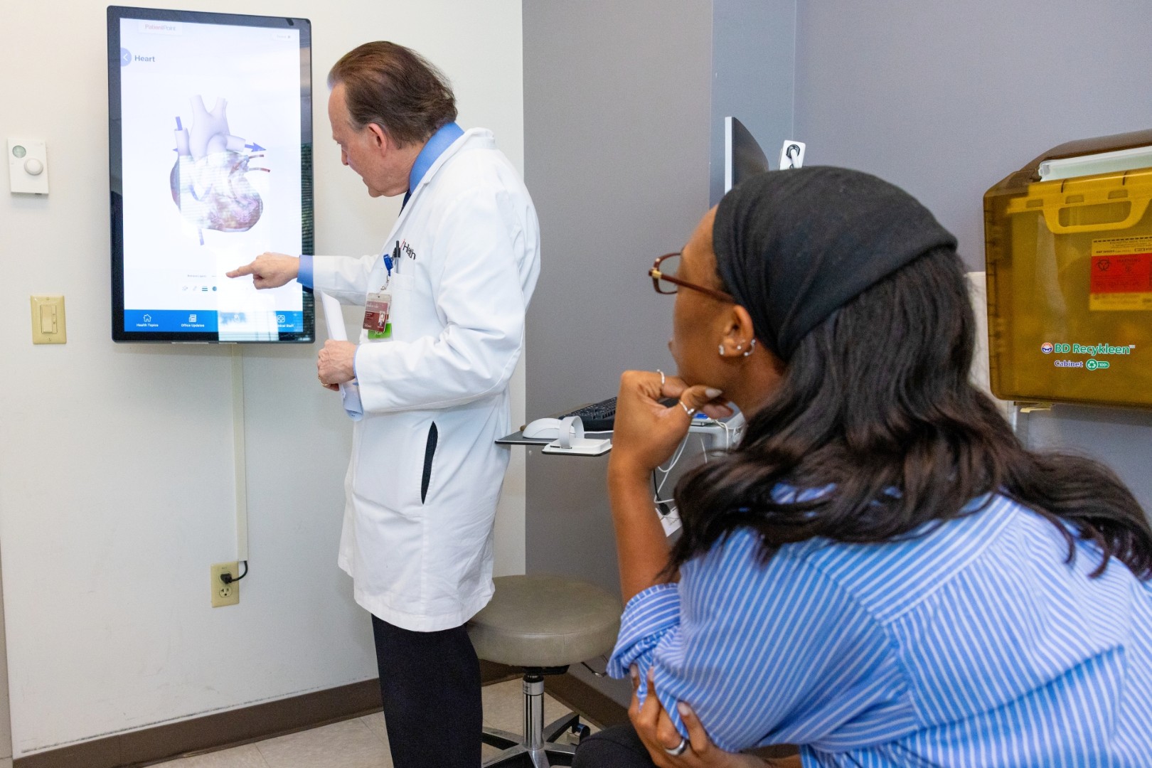 A physician talks with a patient in an exam room. 