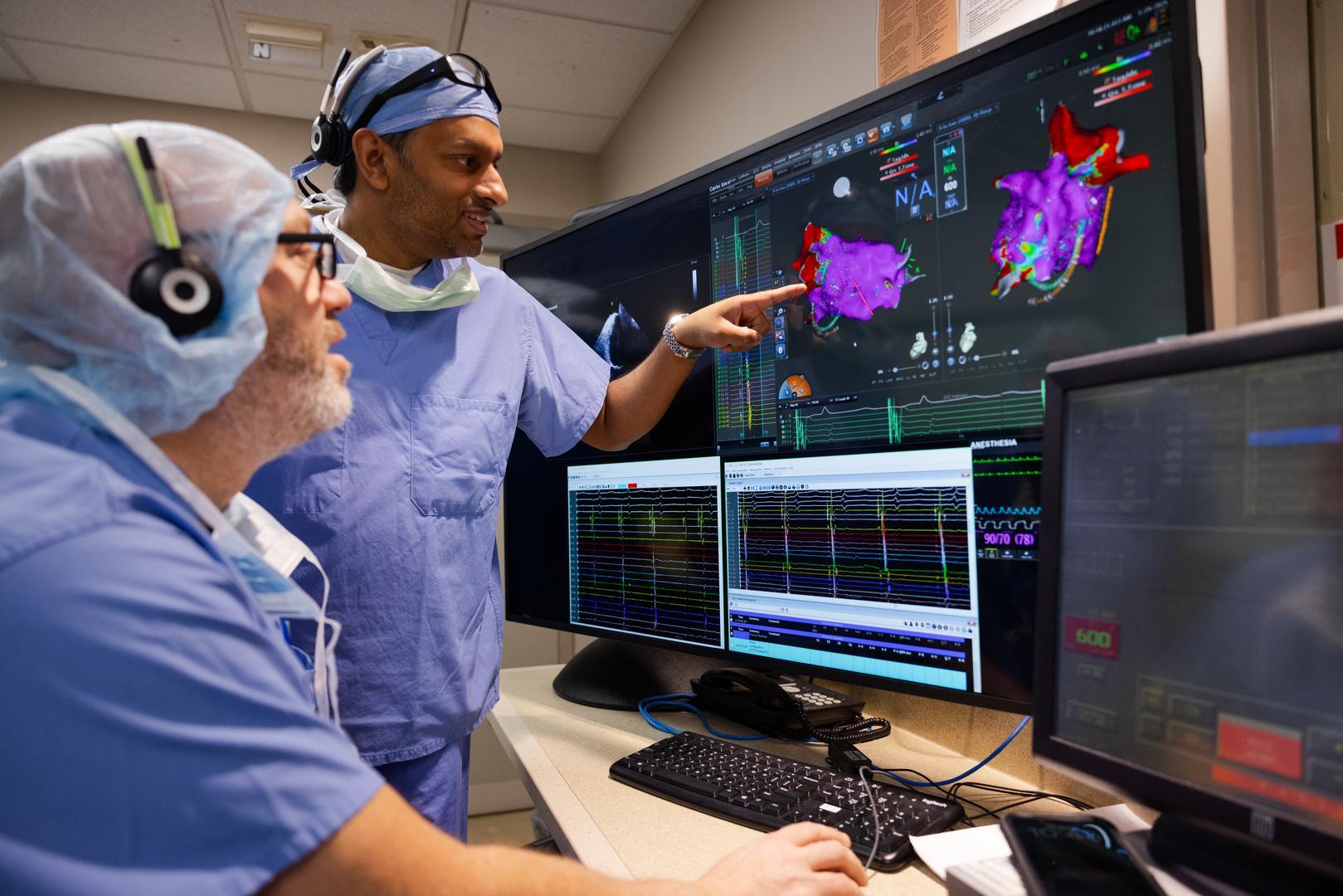 Two medical providers talk and look at a computer monitor. 