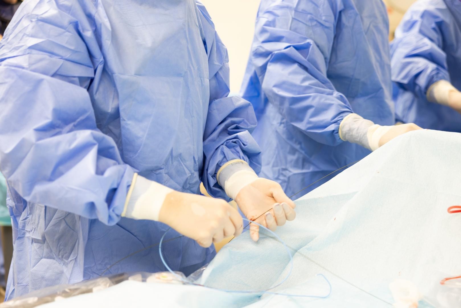 Physicians in scrubs and mask perform a medical procedure.