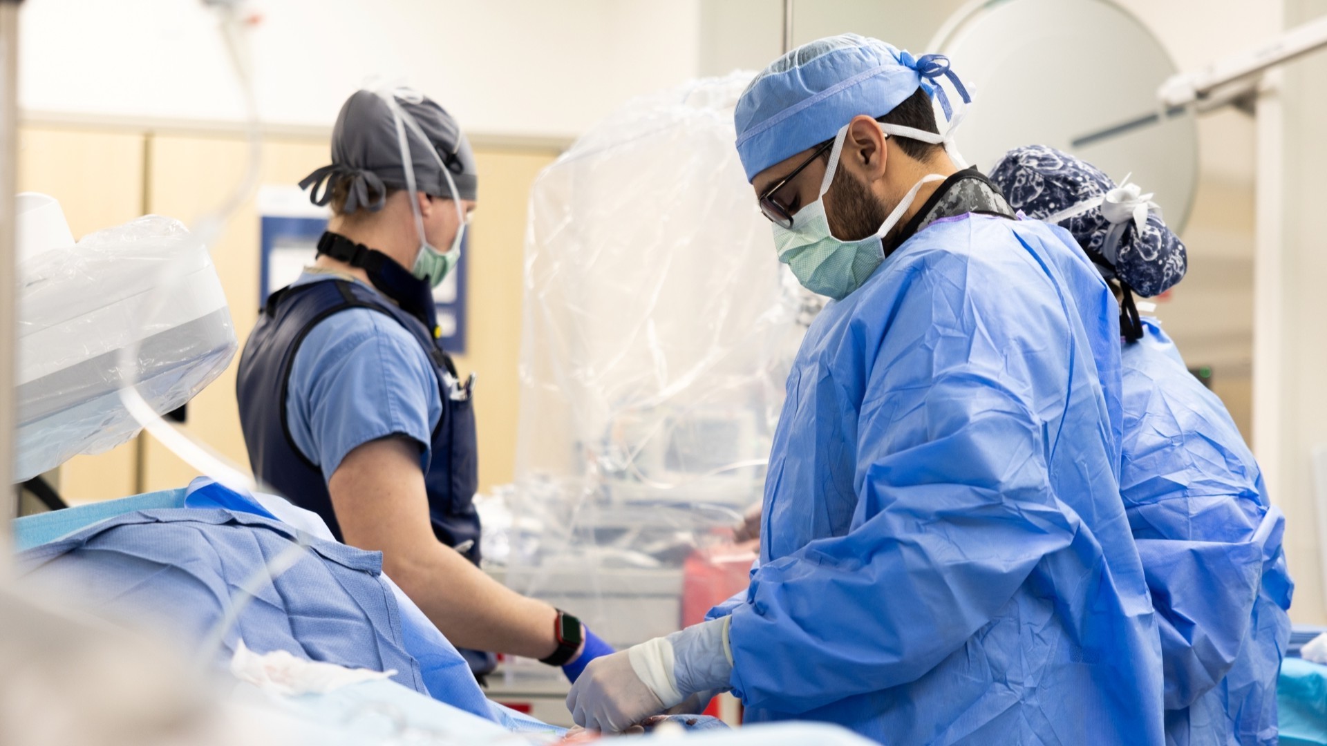 Surgeons in mask and scrubs performs a medical procedure.