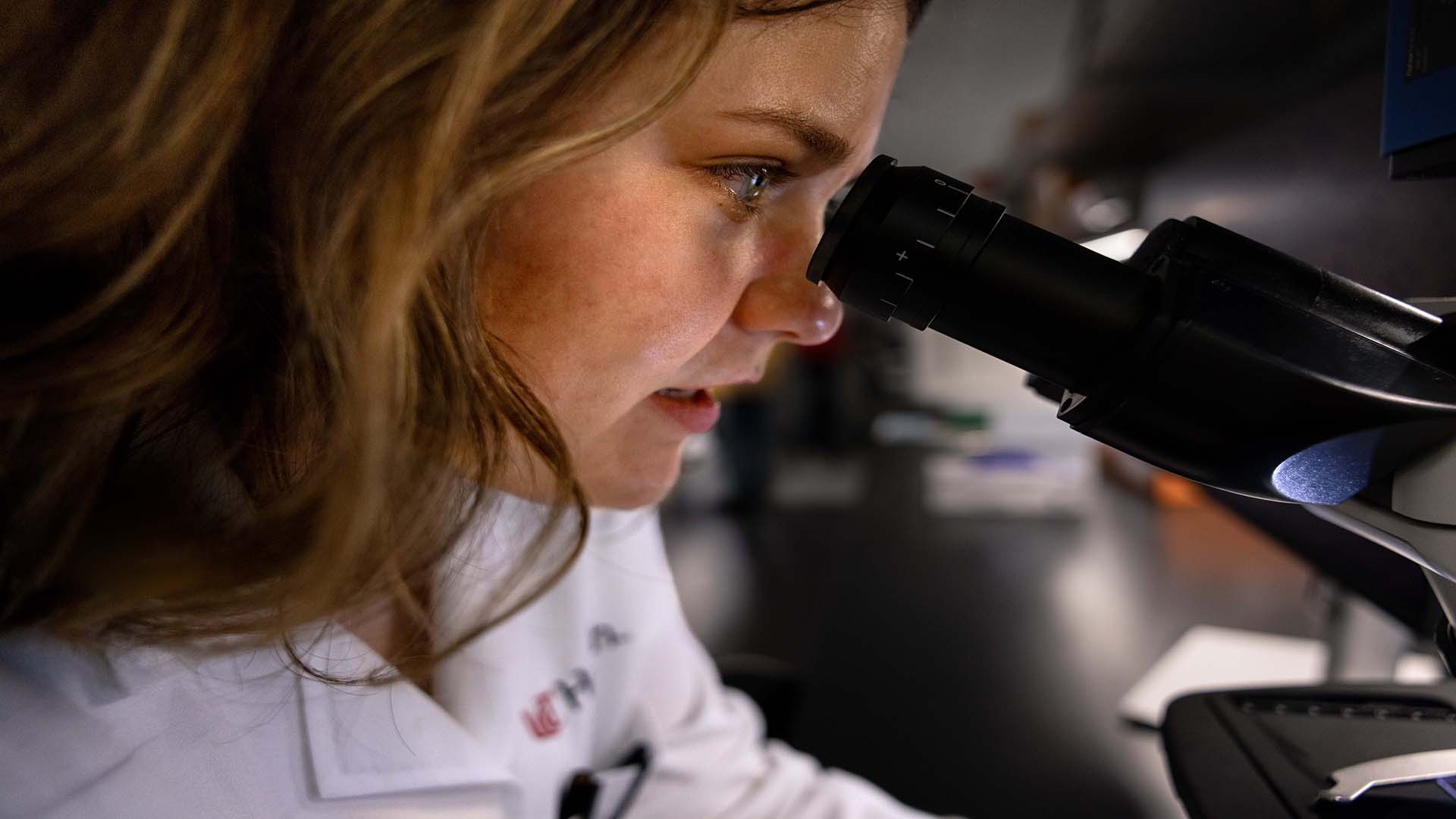 A cancer researcher looks into a microscope.