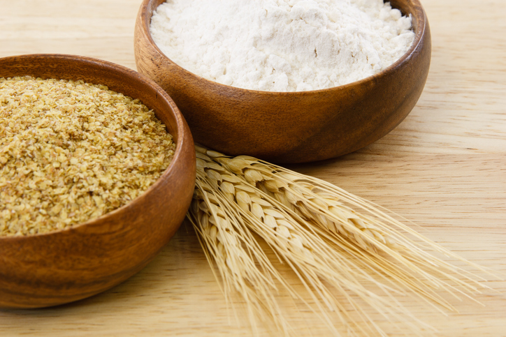 Grains in bowls surrounding wheat. 