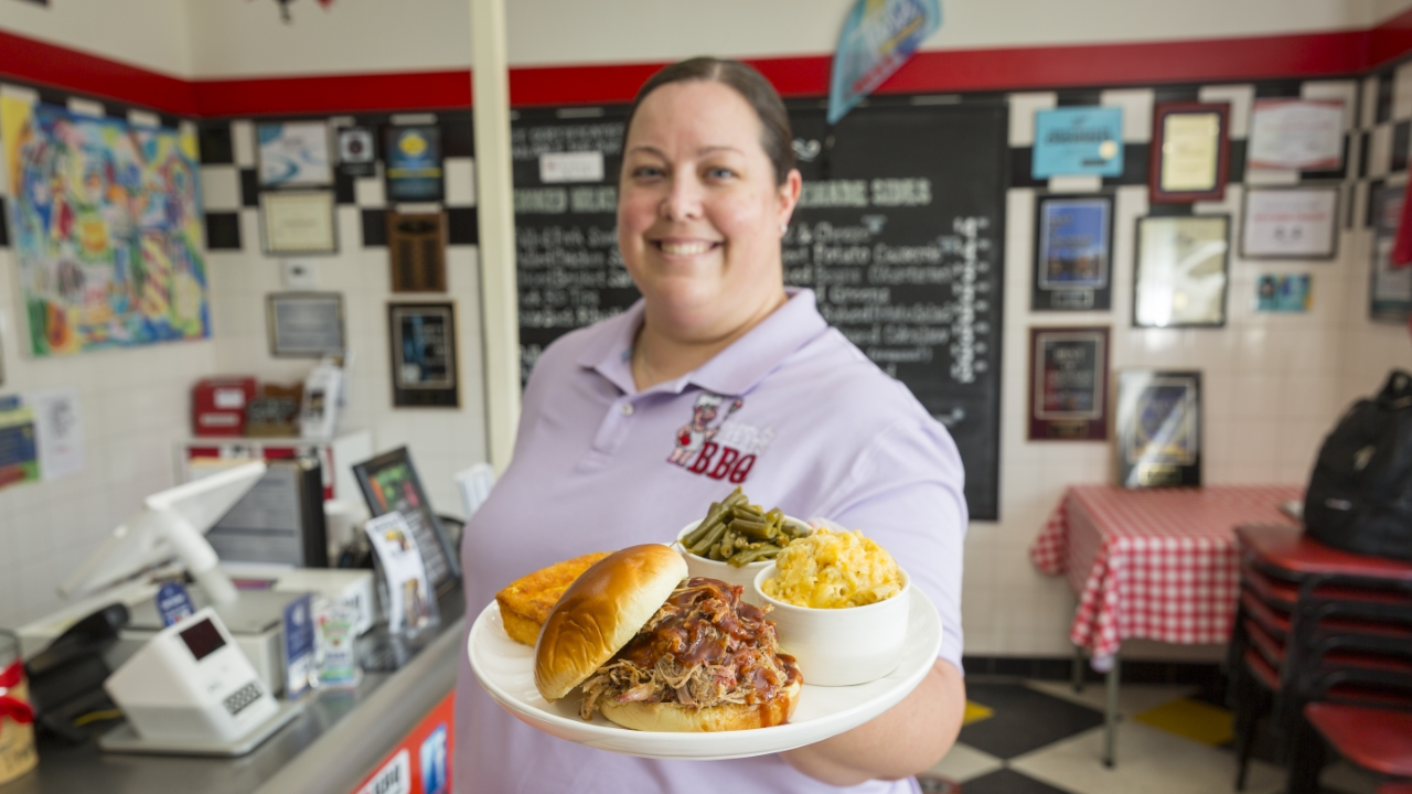 Kristen showing off a plate of delicious food at her restaurant