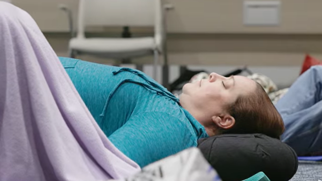 Kristen lays on floor with eyes closed during sound bath therapy