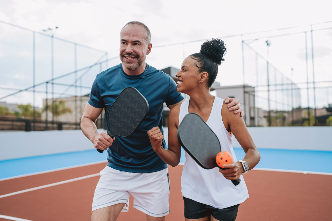 Couple smiles together on a pickleball court