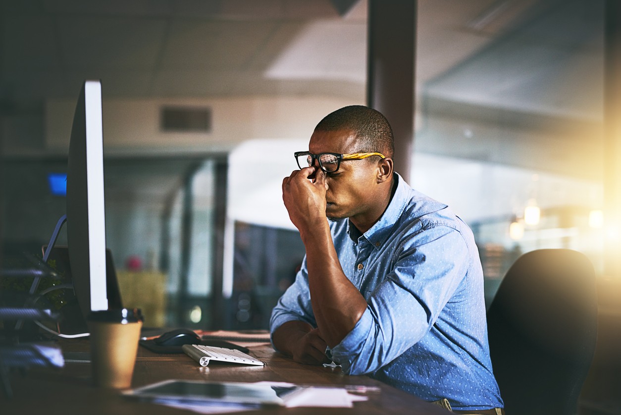 Man appears stressed at a desk in an office setting