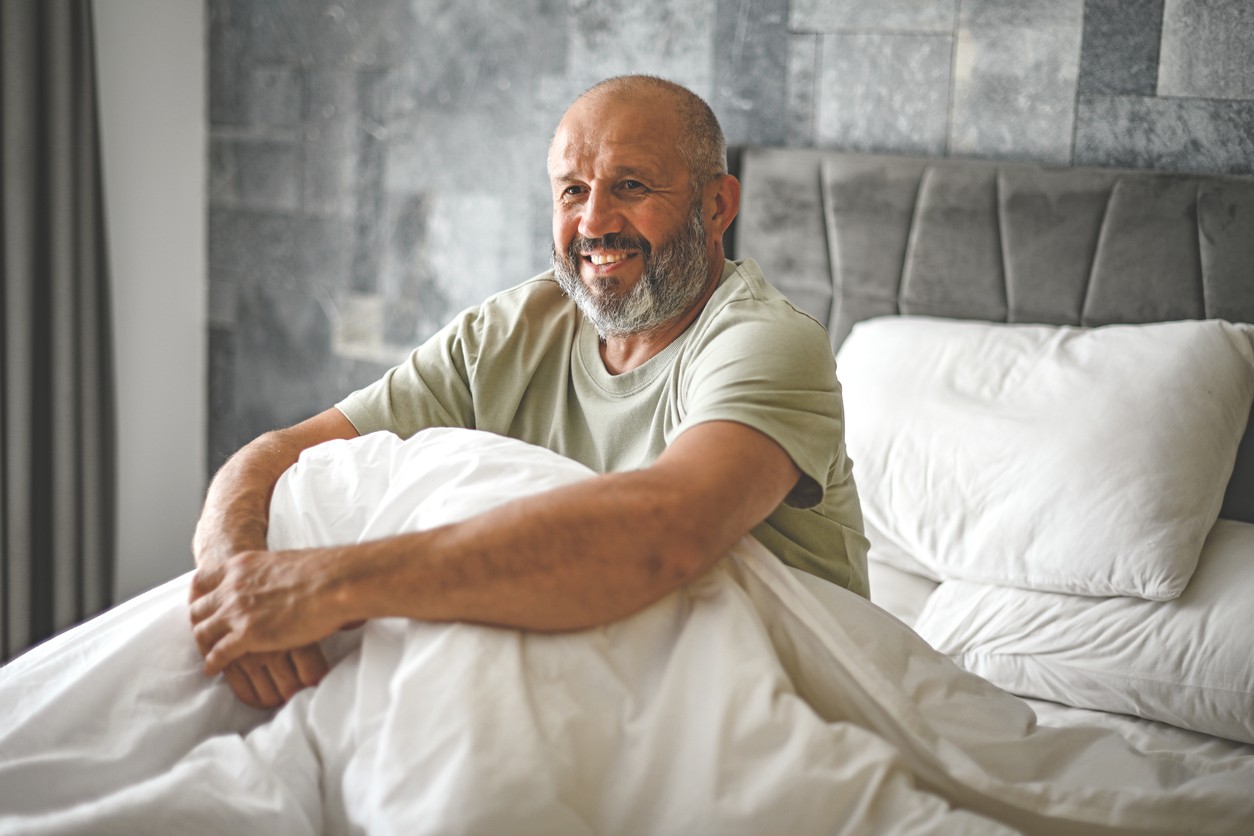 Man smiles in bed after a restful night sleep