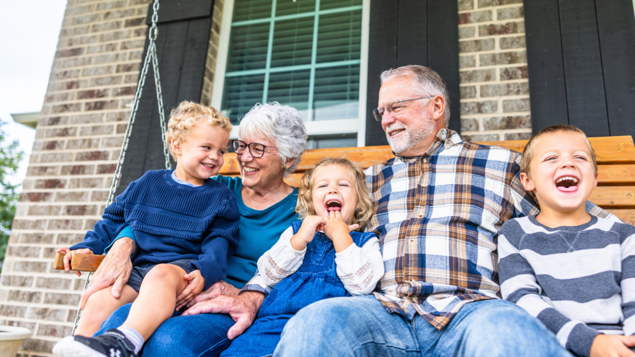 Patient and their support partner sit on a porch swing with three children