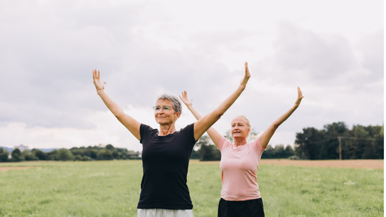 Two women stand in a field and practice Tai Chi