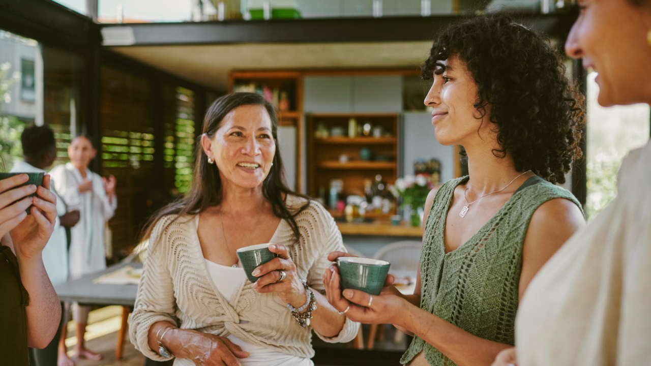 Women stand and talk over cups of tea at a retreat