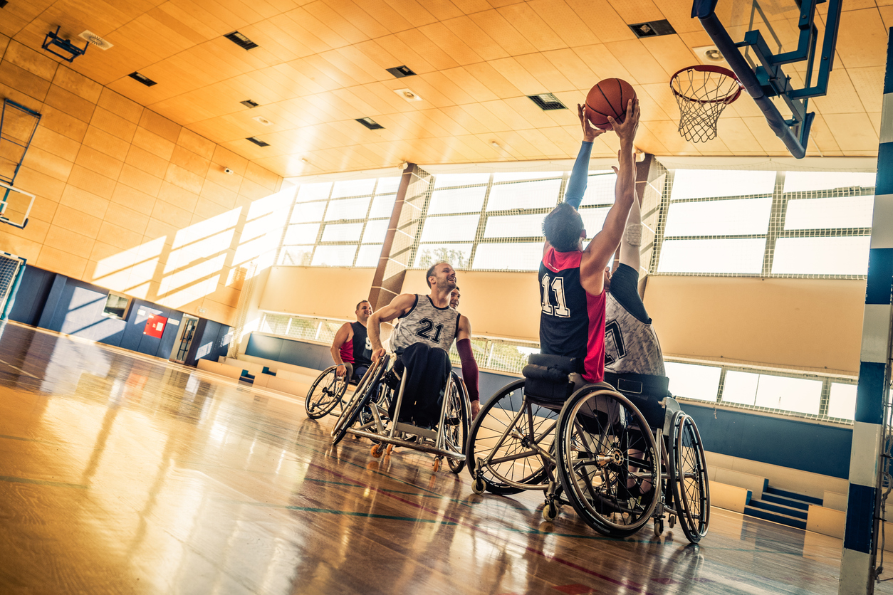 Athletes playing basketball using wheelchairs in gym