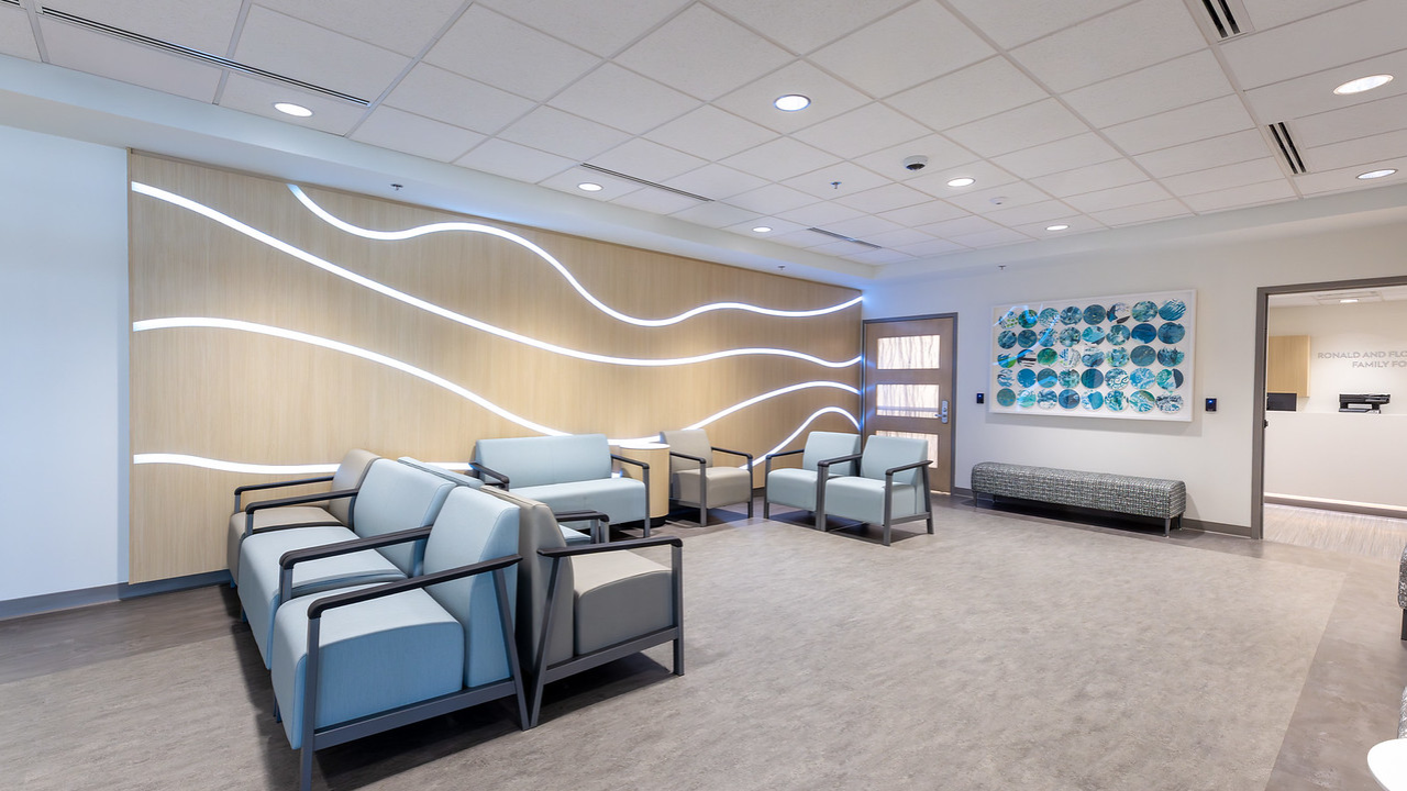 Lobby of the Freeman Center's patient lobby with couch and chair seating, light mural and patient artwork