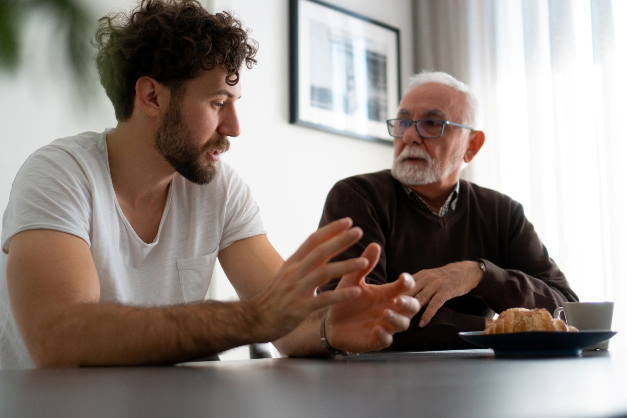 Two men sit at a table and talk. 