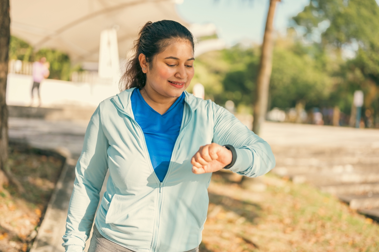 Woman checks her watch as she walks outside on a sunny day.