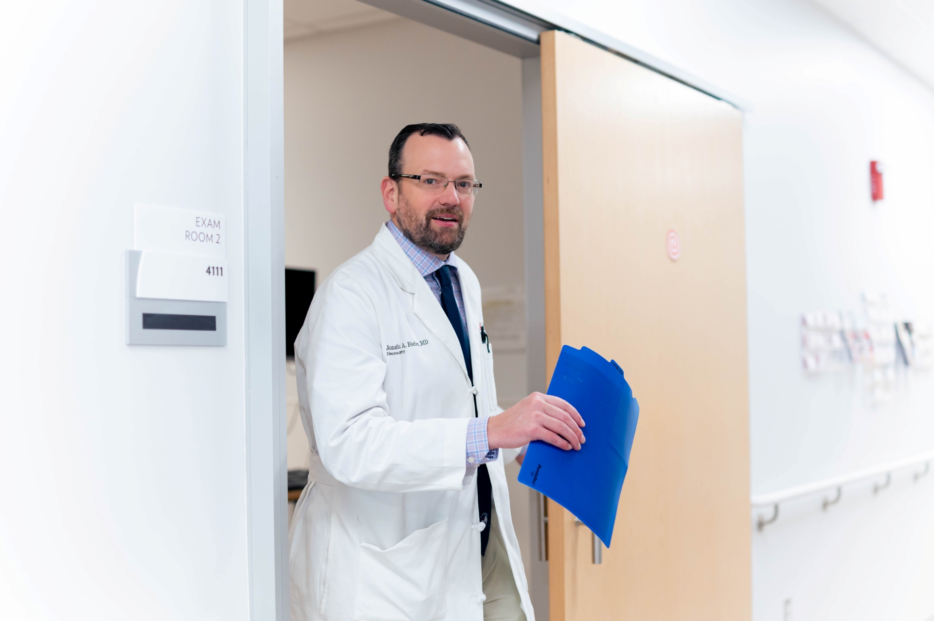 Physician walks from a medical room into the hallway. 