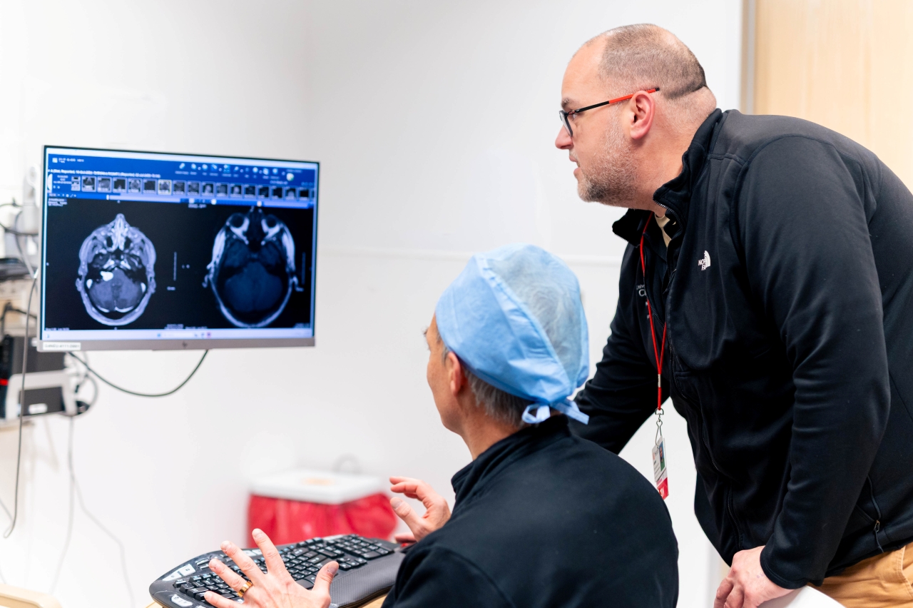 Two medical providers review a scan on a monitor. 