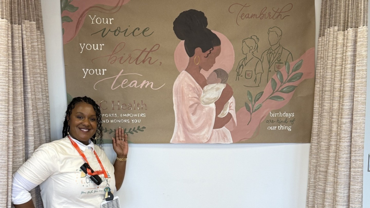 Labor and delivery nurse educator, Shaunda Dawson, RN, stands with a Teambirth mural.