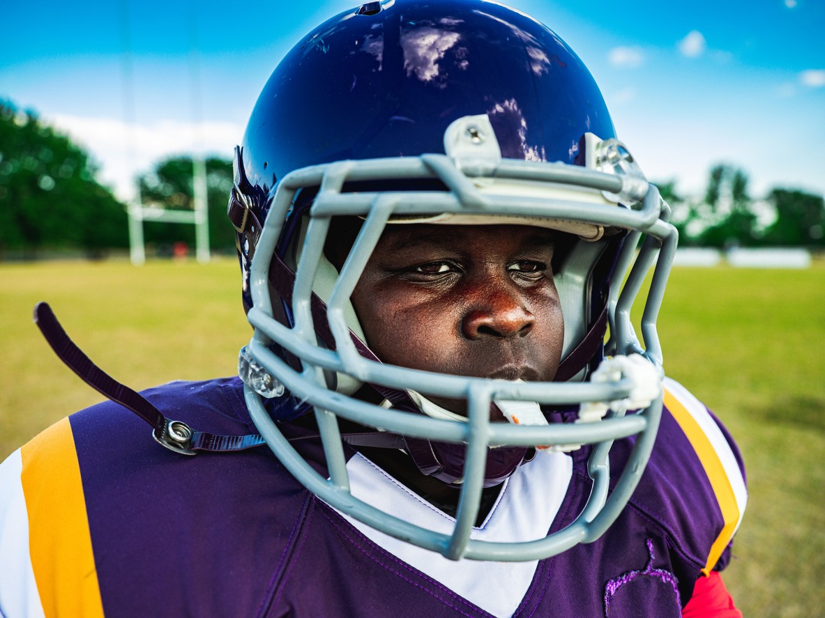 Young man wearing a purple football helmet and protective equipment on a football field