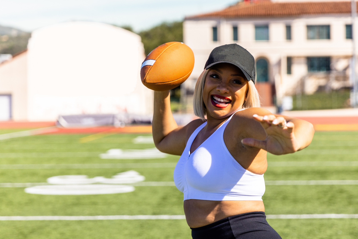 Woman throws a football on a football field