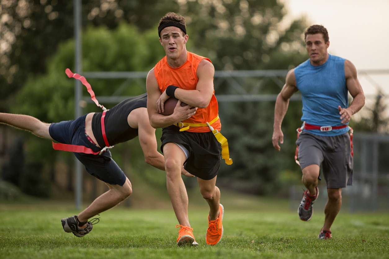 Three men play flag football 