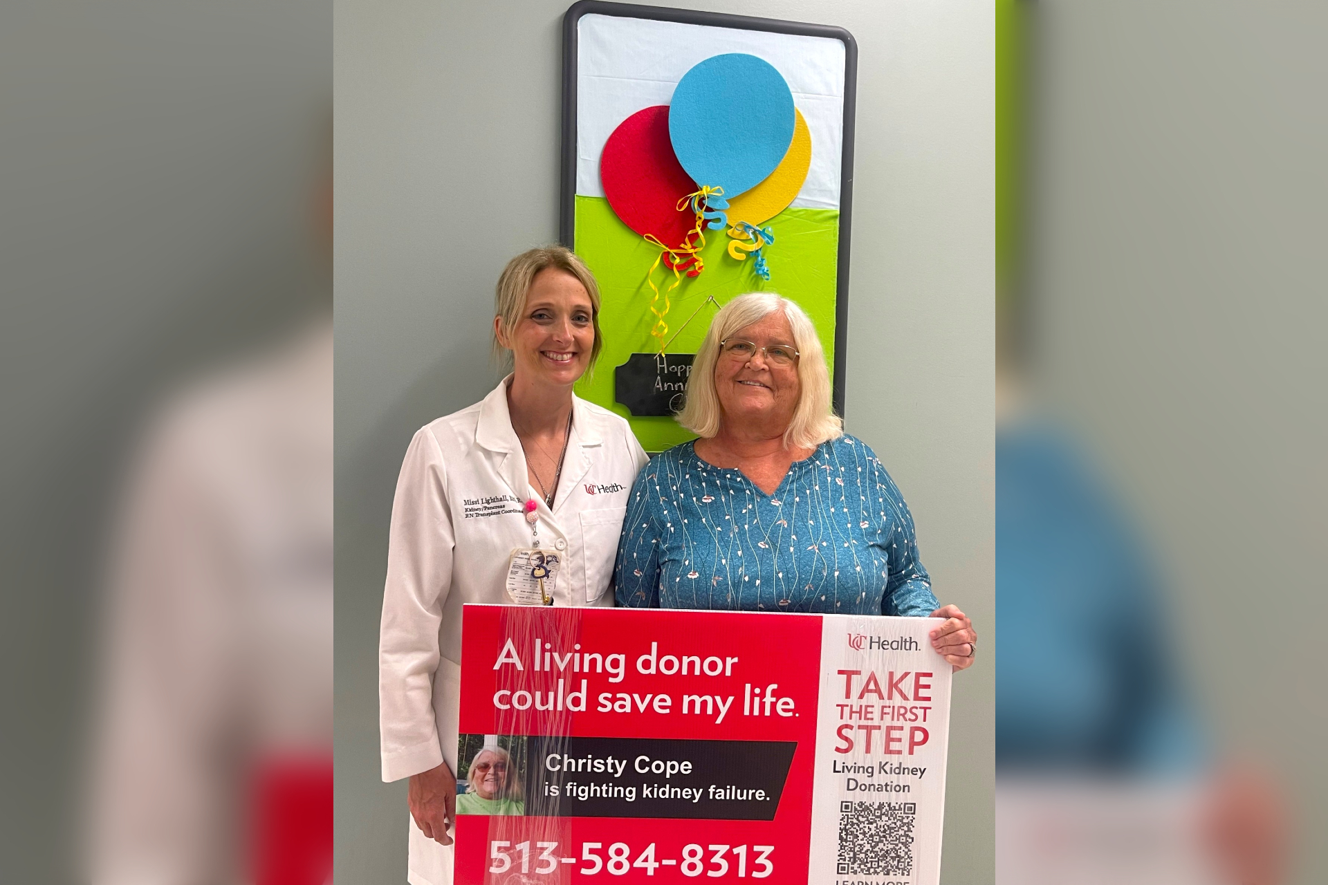 Physician stands next to a patient holding a living donor yard sign. 
