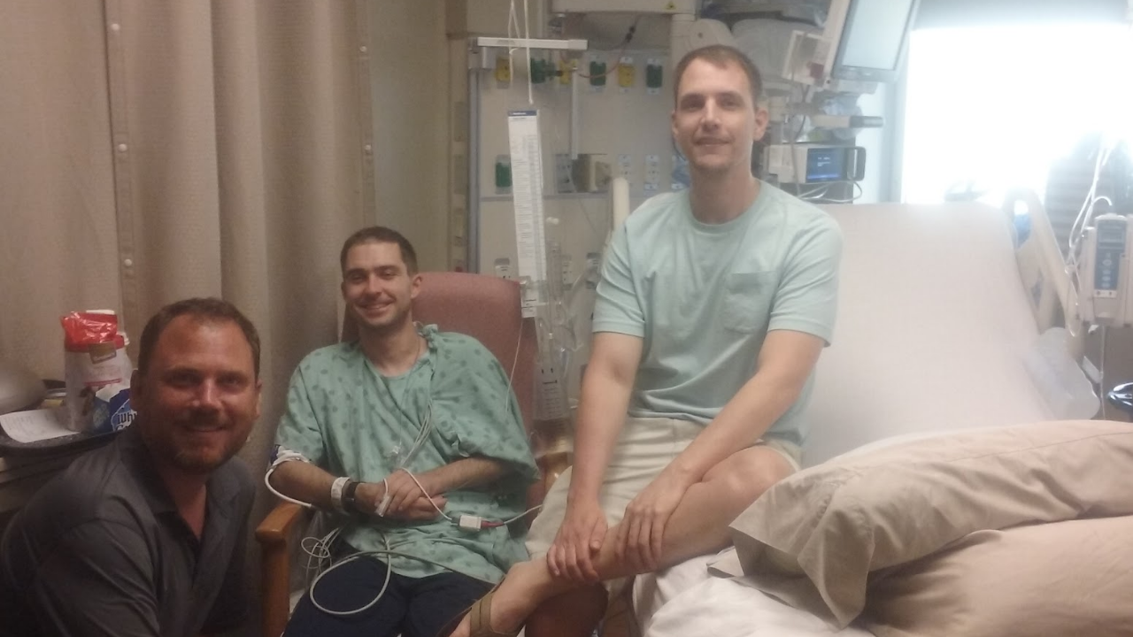 Adam is visited by friends in the hospital in 2019