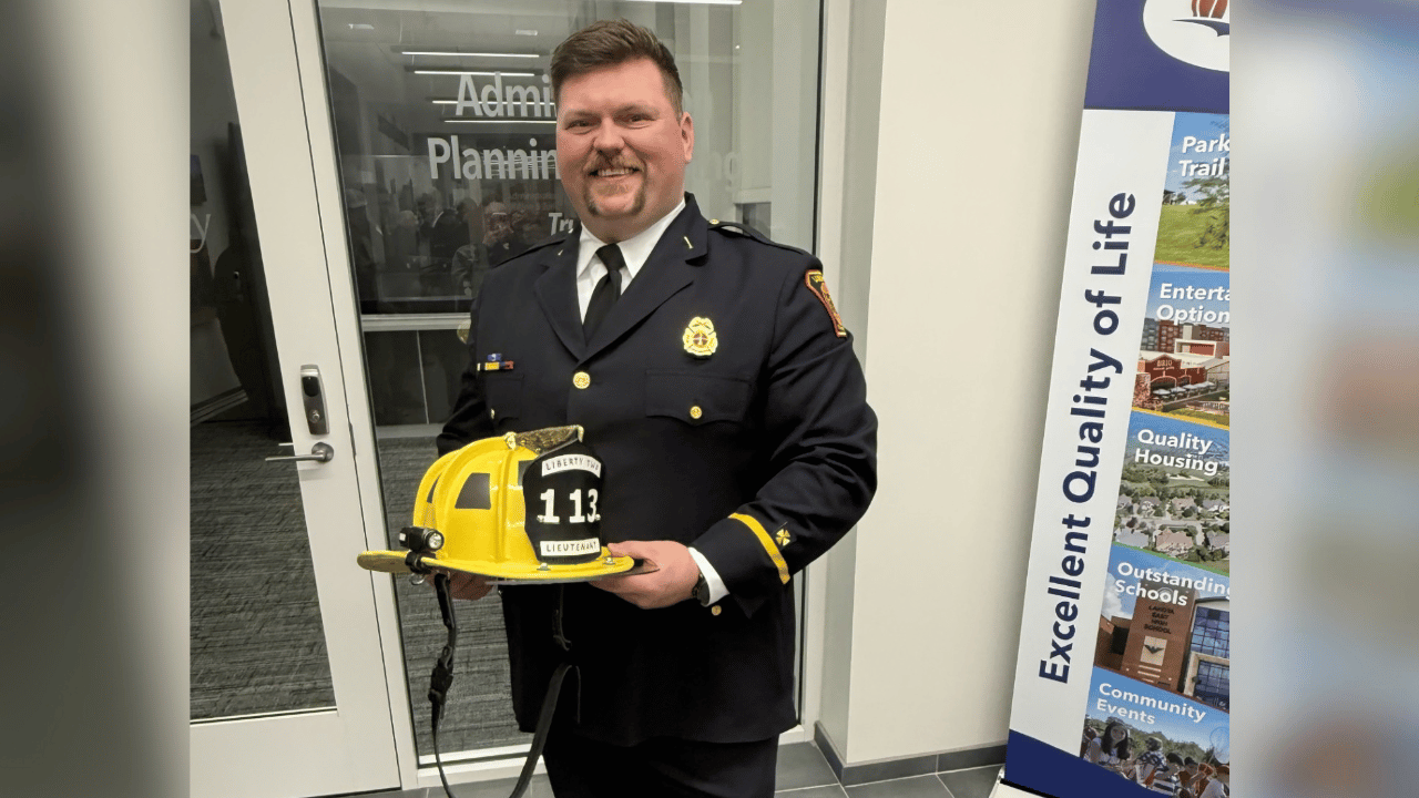 Firefighter Austin smiles in his dress uniform while holding his hat.
