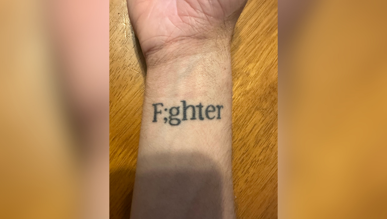 Daniel shows a tattoo that says "F;ighter" on his wrist 