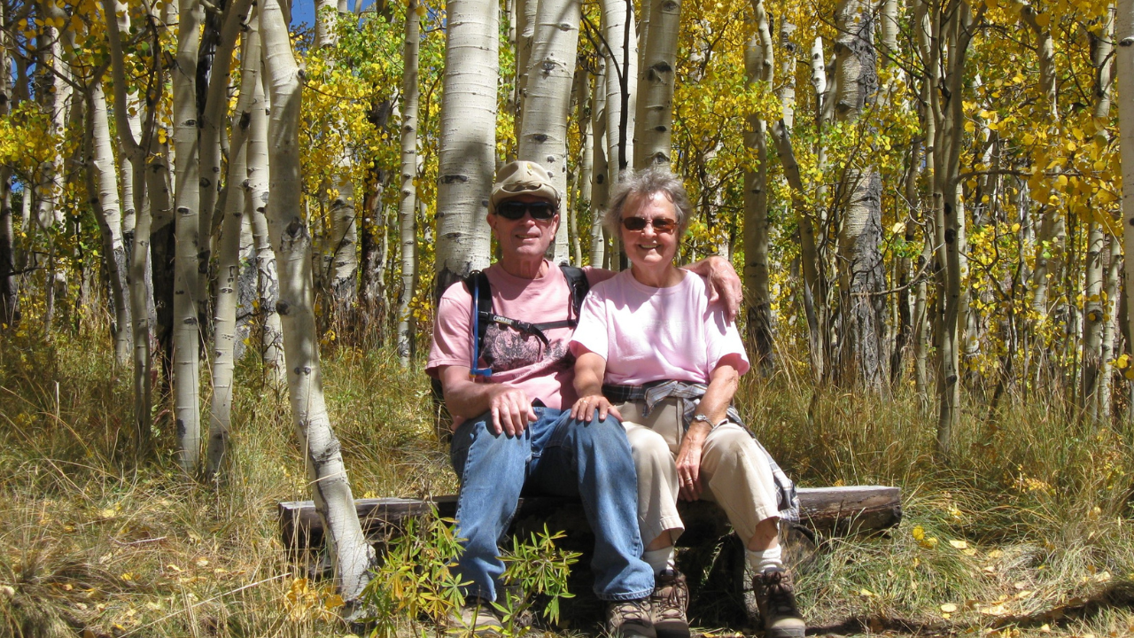 Dave Ebner and his wife Carole sit amongst birch trees on a beautiful fall day