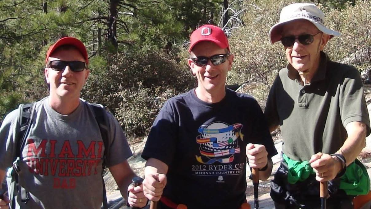 Greg smiles for a photo on a hike with two others