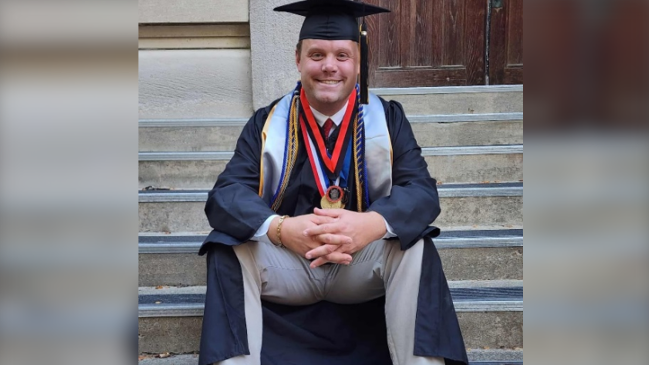 Kurtis sitting on stairs in graduation regalia