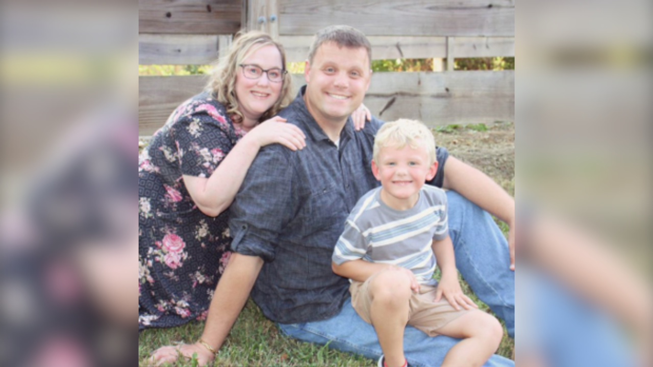 Kurtis smiles for a family photo with his wife, Brittany, and son, Maverick