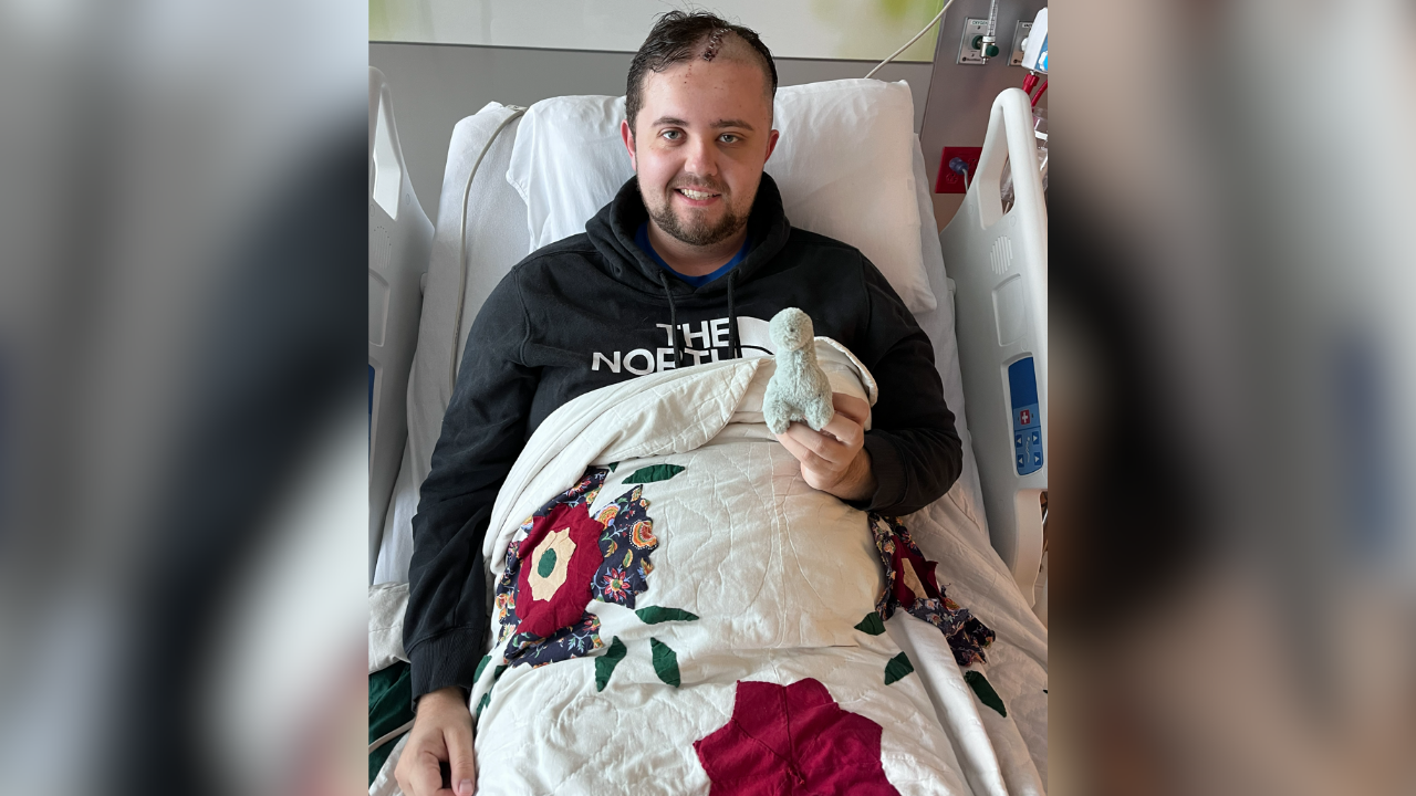 Mason recovering in a hospital bed, holding a small stuffed animal and under a quilt