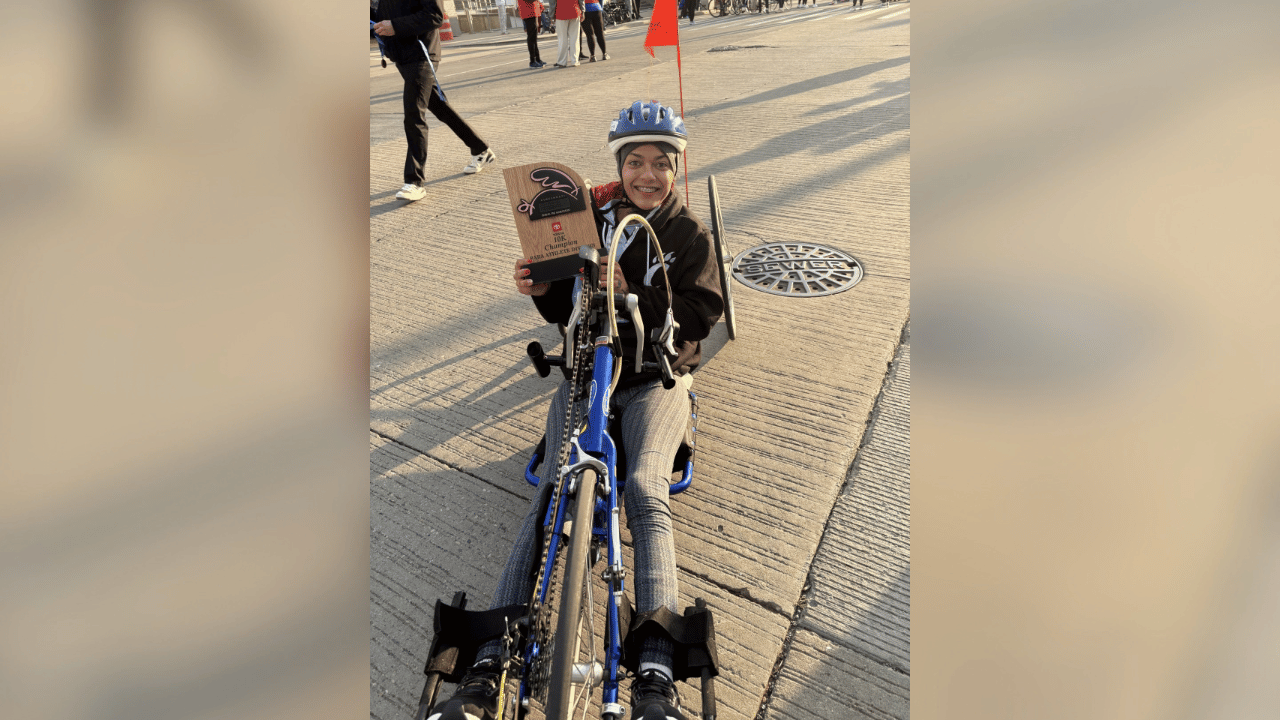 Mikiahya proudly holds the plaque she earned after crossing the half marathon finish line in her handcycle.